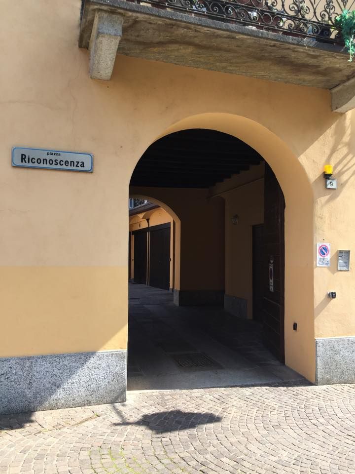L'androne ad arco del cortile di Piazza Riconoscenza 9 a Saronno, con l'intonaco ocra e lo zoccolo in granito